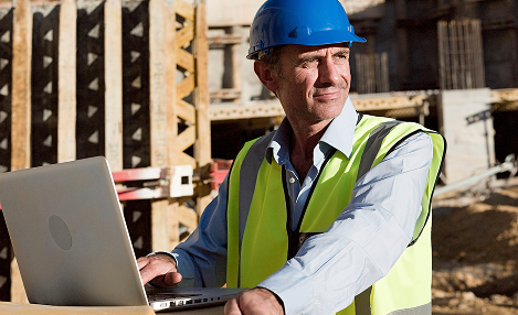 Superviseur avec ordinateur sur chantier.